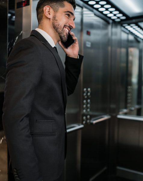 Portrait of young businessman talking on the phone at the hotel elevator. Business travel concept.