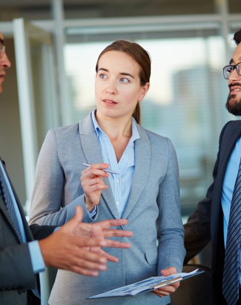 Elegant business partners looking at colleague at meeting